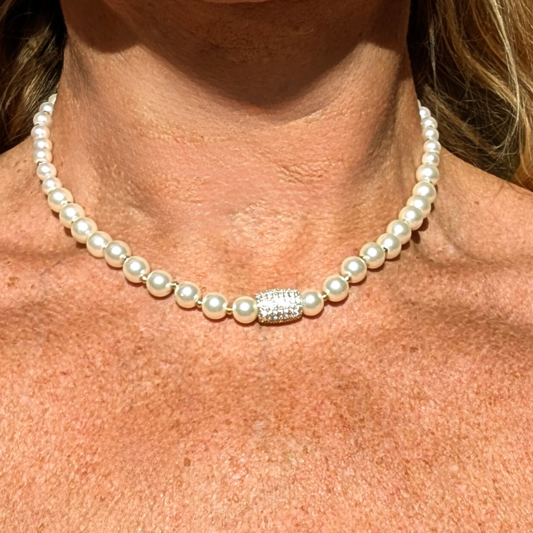 Parel ketting afgewisseld met goudkleurige kraaltjes en een bedel met strass