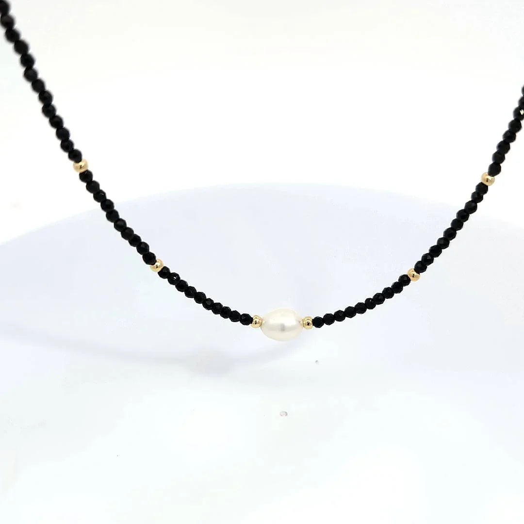 Zwarte kraaltjes ketting met kleine goudkleurige kraaltjes en een grote ovale parel - Casa Jadel