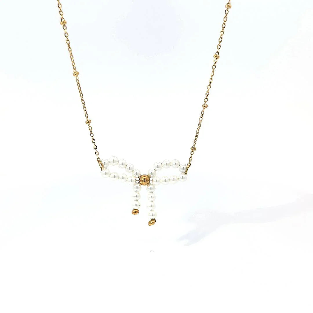 Fijne schakel ketting met balletjes en een parelkraal strik met goudkleurige details - Casa Jadel