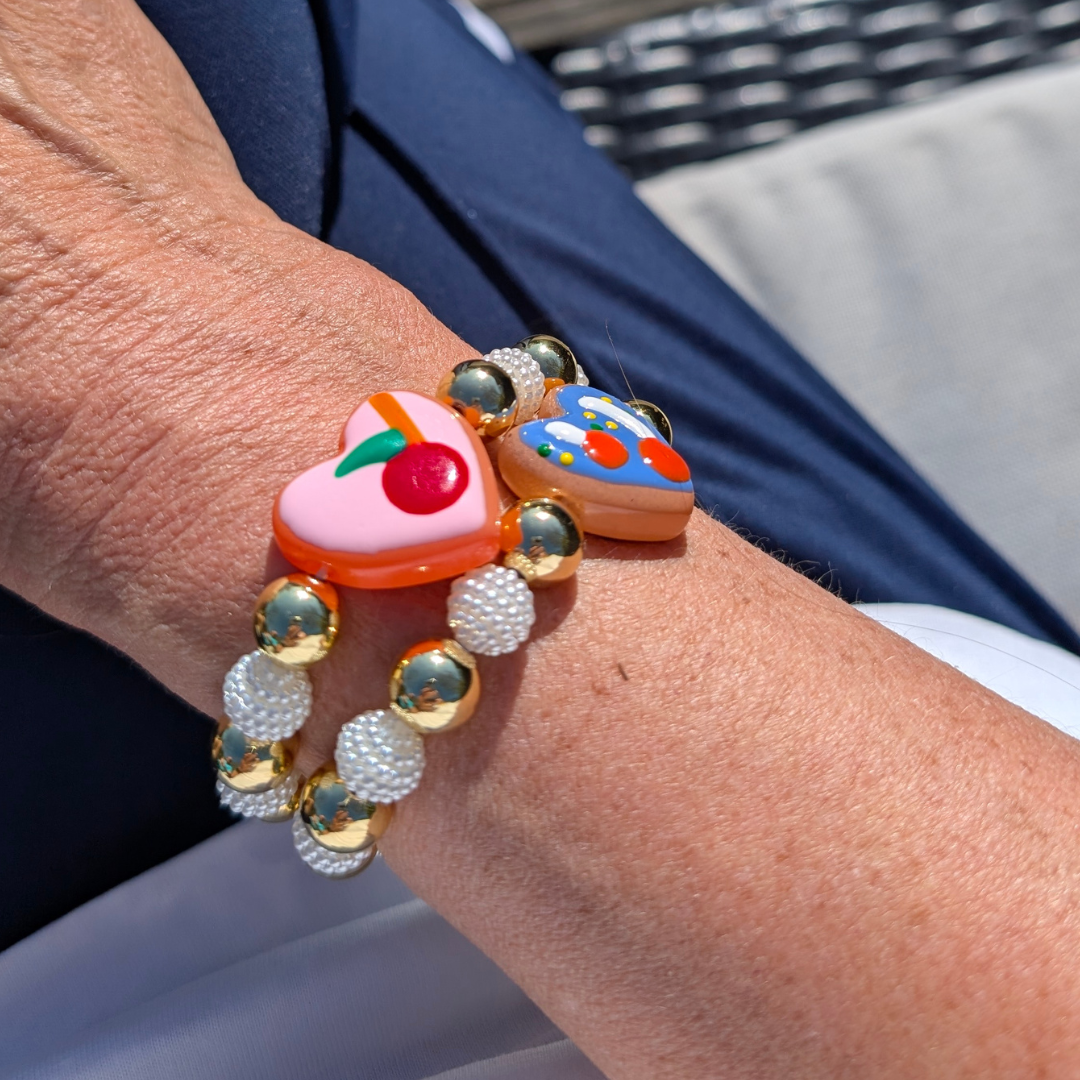 Armband goudkleurige en parelmoer kralen hartvormig blauwe bedel