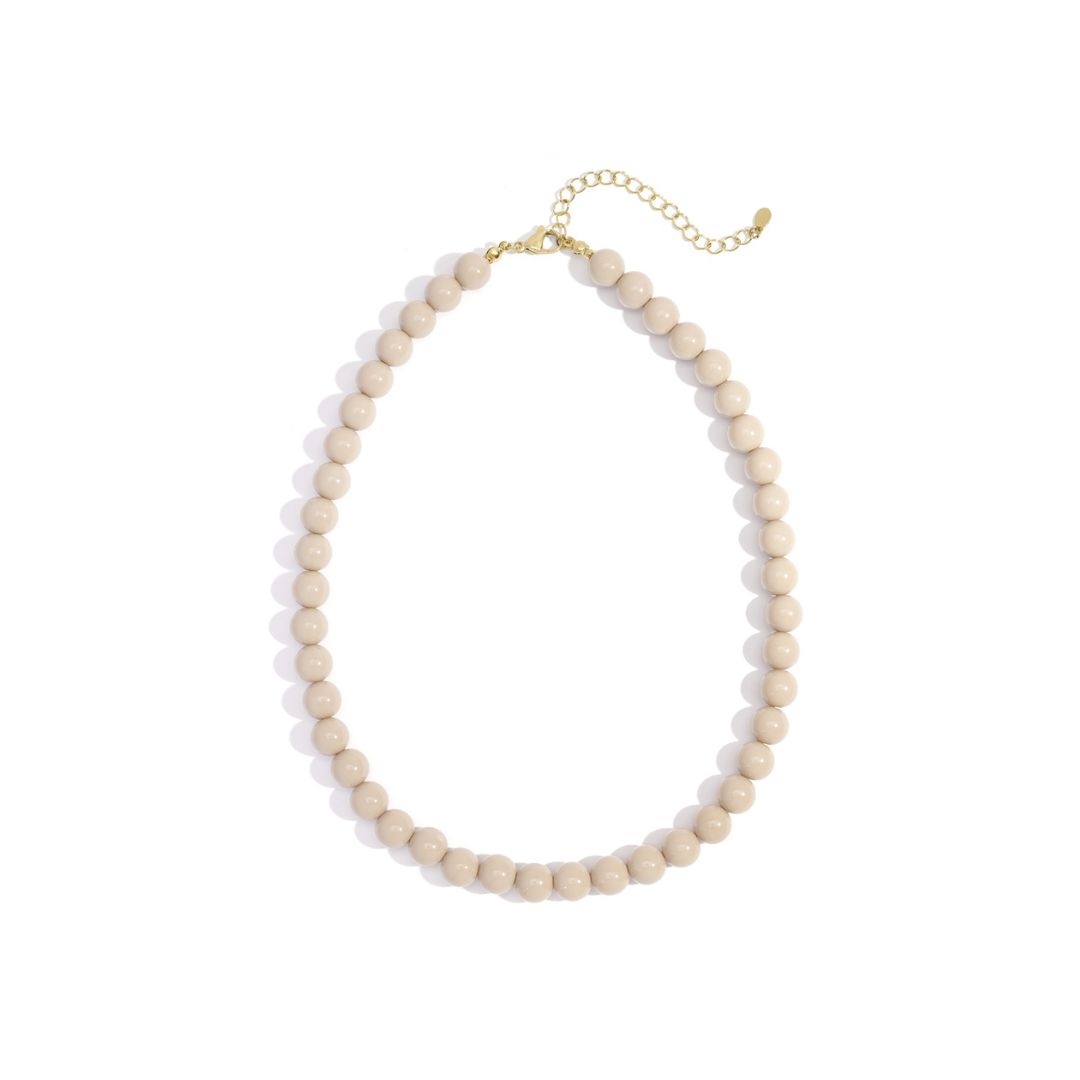 Beige kralenketting met ronde kralen en goudkleurige sluiting op witte achtergrond