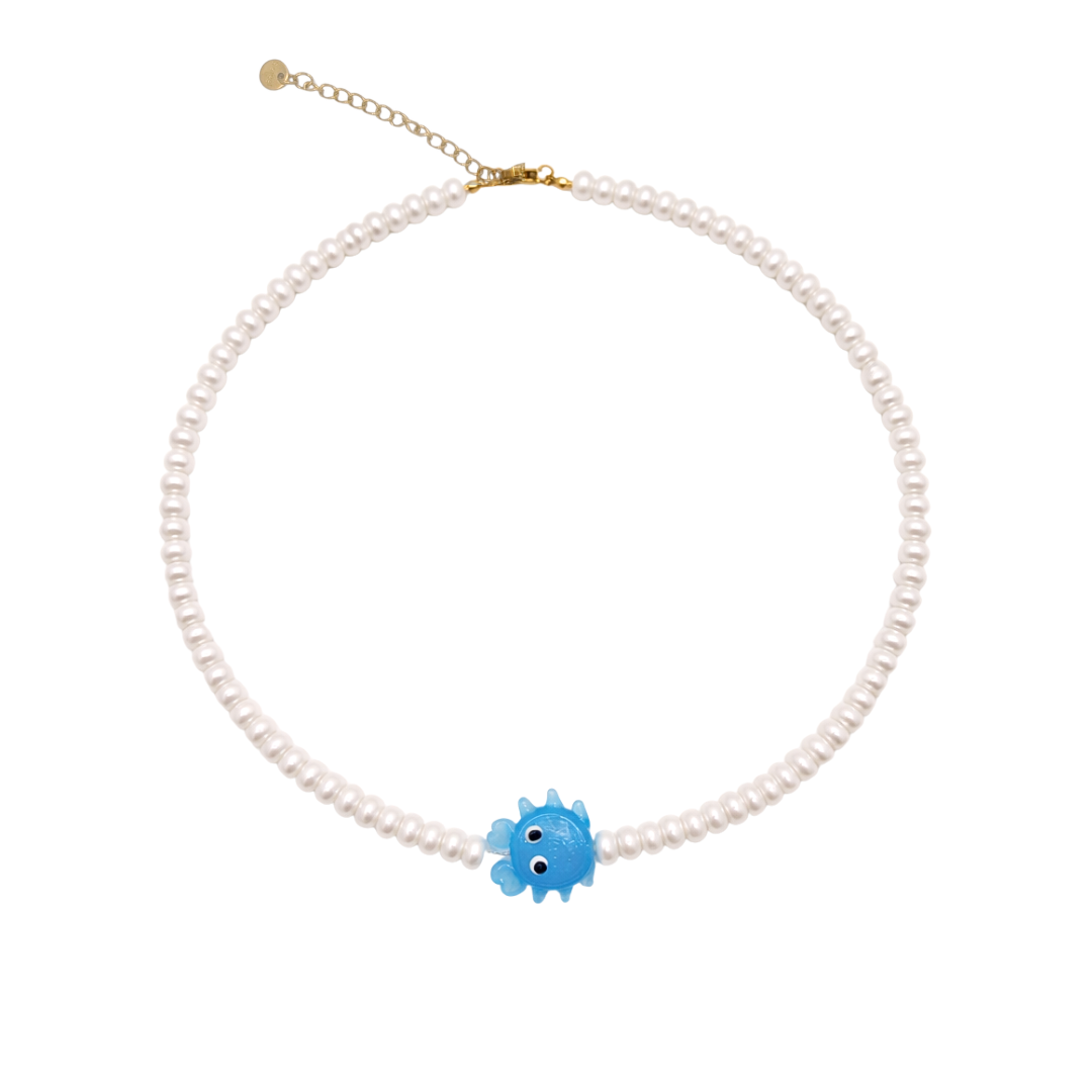 Parel kralenketting met kleine witte parelkralen en blauwe krabbedel op lichte achtergrond