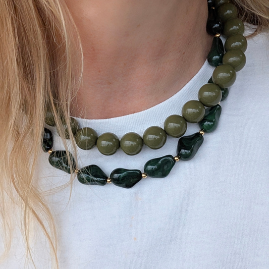 Model draagt meerdere gelaagde kettingen als necklace stack