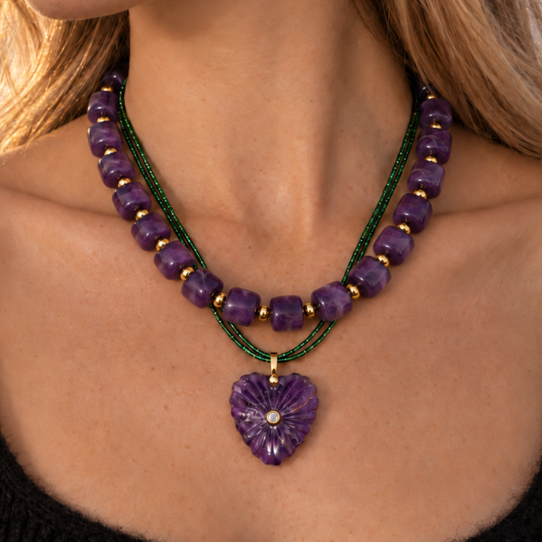 Model draagt een paarse kralenketting en een groene rope ketting met amethist hartbedel.