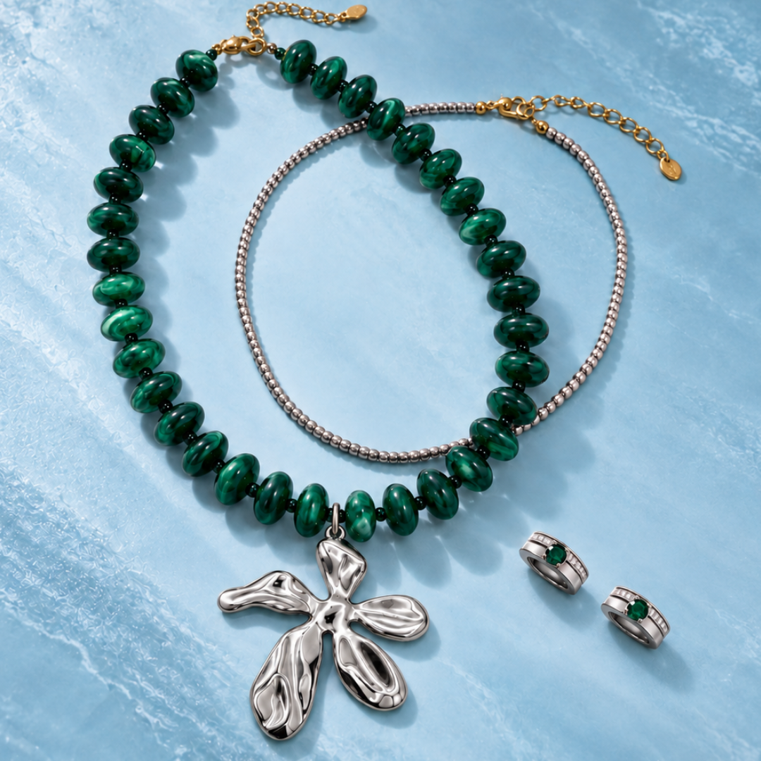 Groene kralenketting met zilverkleurige bloem, fijne zilverkleurige ketting en een paar oorbellen met groene steentjes.