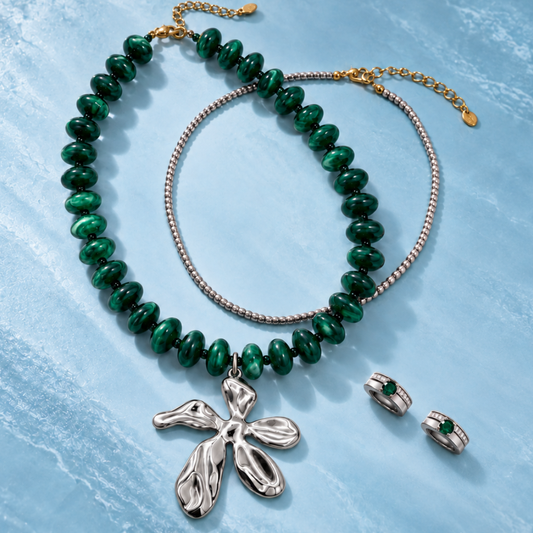Groene kralenketting met zilverkleurige bloem, fijne zilverkleurige ketting en een paar oorbellen met groene steentjes.