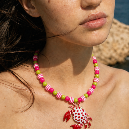 Roze kralenketting met kleurrijke handgeschilderde aardbei en fruit bedels op het strand - Casa Jadel ketting