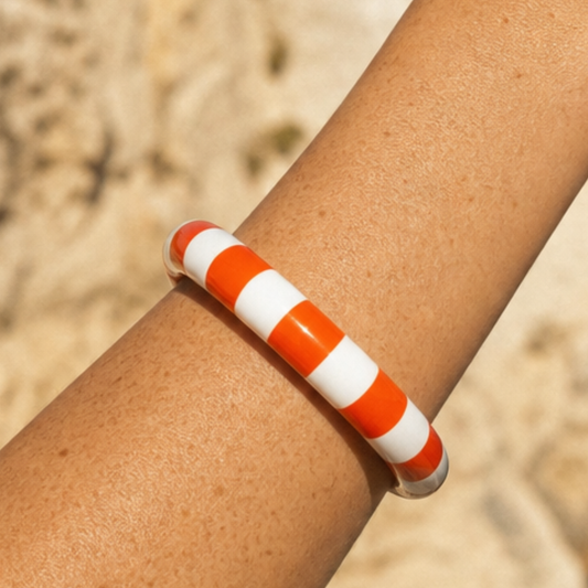 Oranje-witte gestreepte candy bangle armband gedragen op arm bij het strand - Casa Jadel zomerse armband