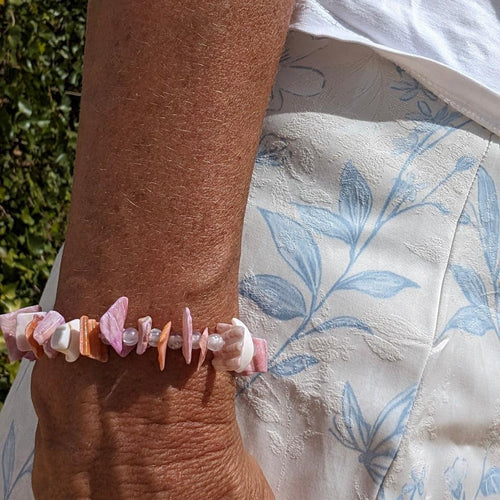 Armband van schelpenstukjes en kraaltje mix met roze zalm kleurige stukjes