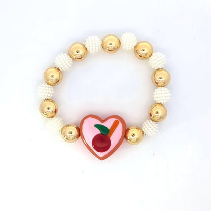 Armband goudkleurige en parelmoer kralen hartvormig roze bedel