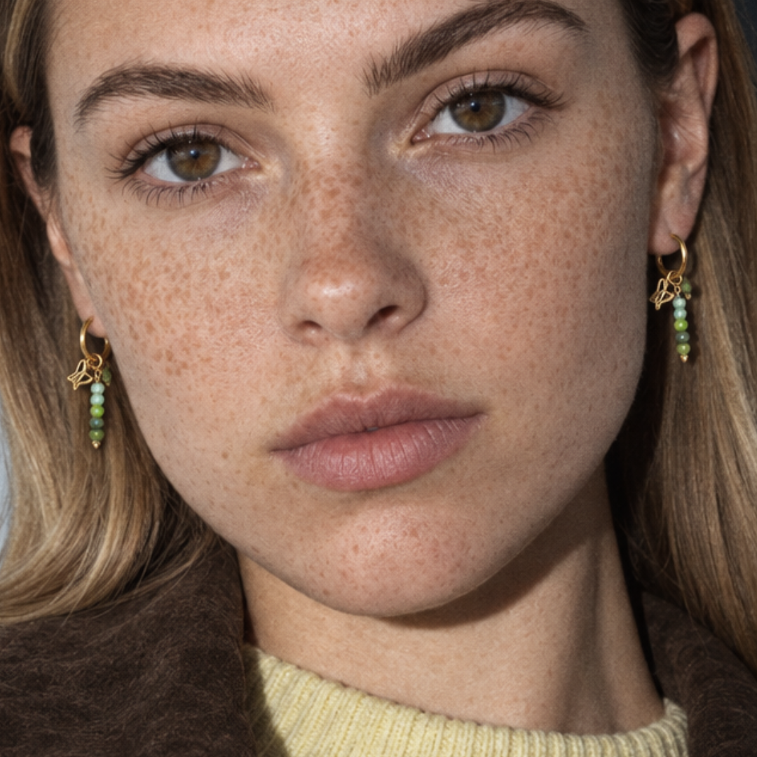 Gouden oorbellen met groene kraal hangers, close-up van model - Casa Jadel