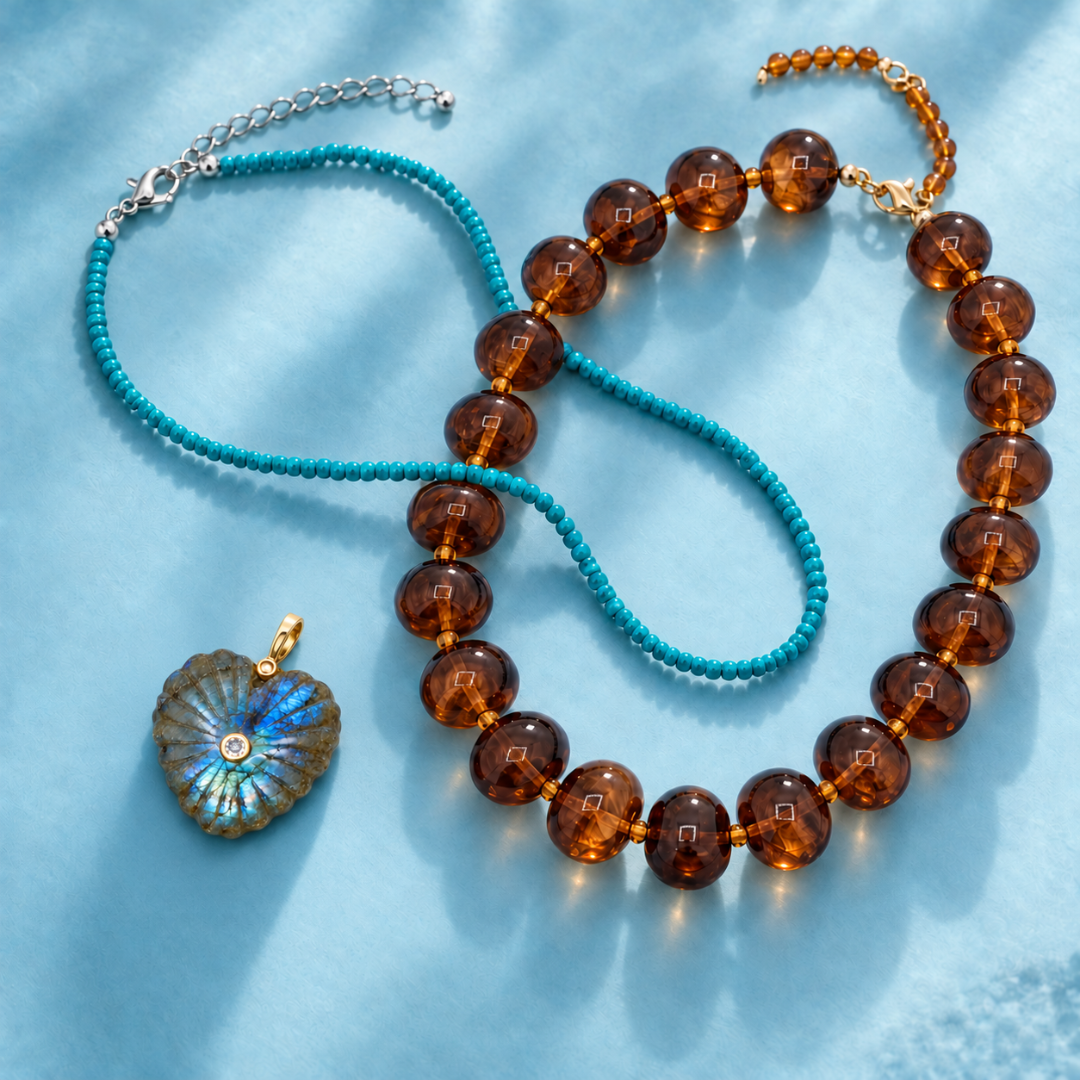 Fijne turquoise kralenketting naast een ketting met grote amberbruine kralen en een losse labradoriet hartbedel.