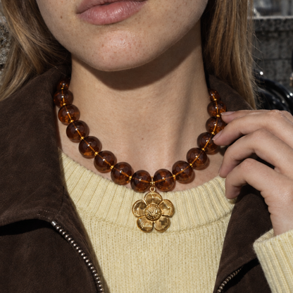 Amberkleurige kralenketting met gouden bloem hanger over gebreide trui - Casa Jadel