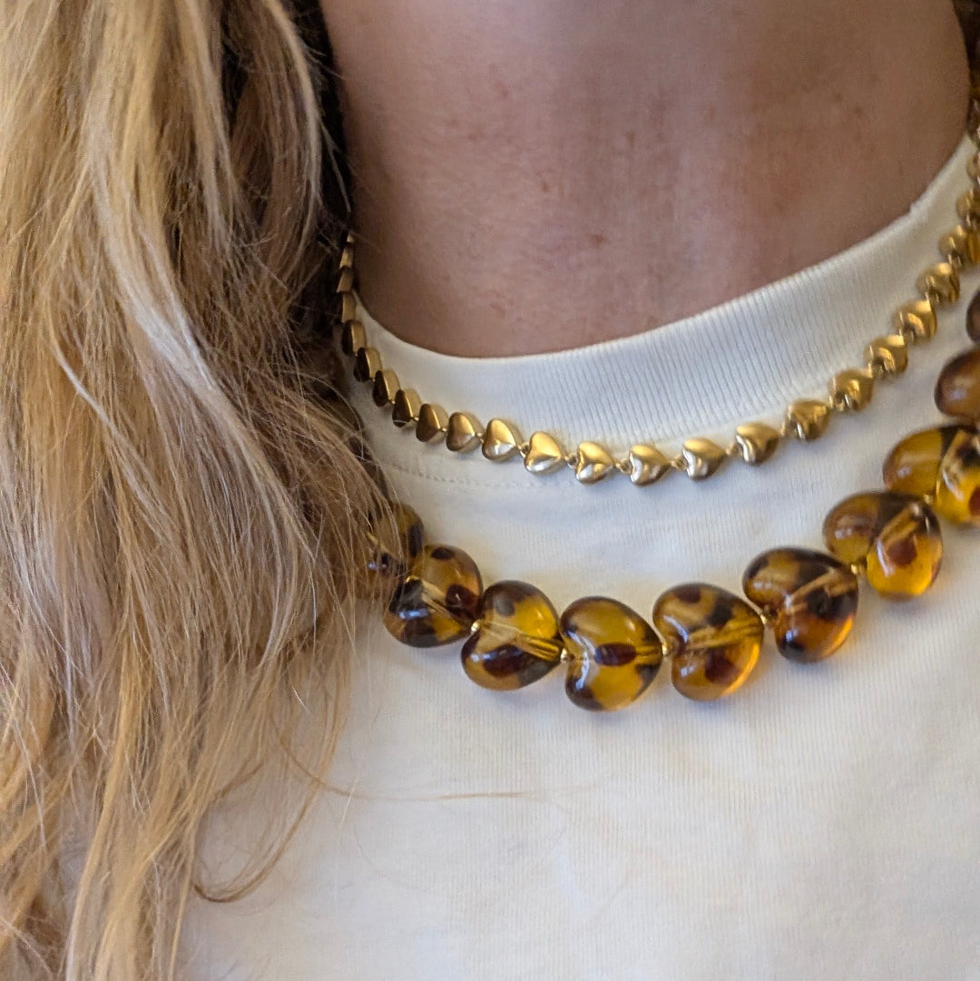 Amber bruin panterprint grote hartjes ketting en gouden kleine hartjes ketting op model