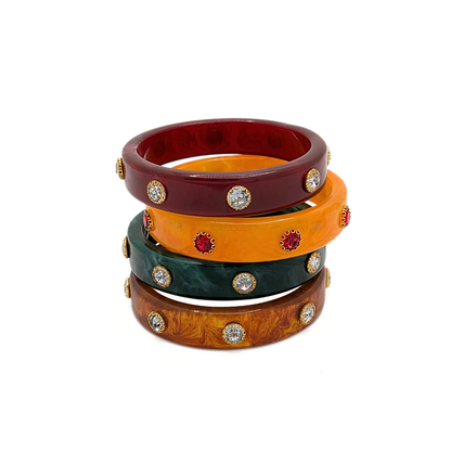 Bruin, groen, rood, oranje bangle armbanden gestapeld op witte achtergrond.