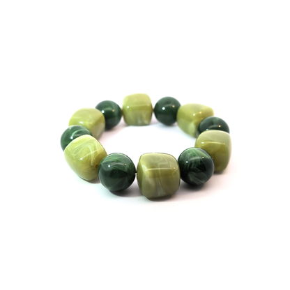 Grote kralenarmband in legergroen en lichtgroen met gemarmerde kralen, chunky Ibiza style armband schuin gefotografeerd op witte achtergrond.