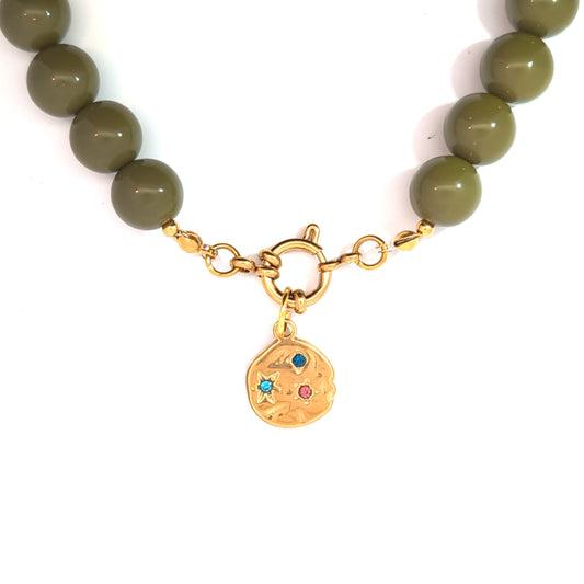 Close-up van gouden cosmic munt bedel bevestigd aan boeislot van kralenketting