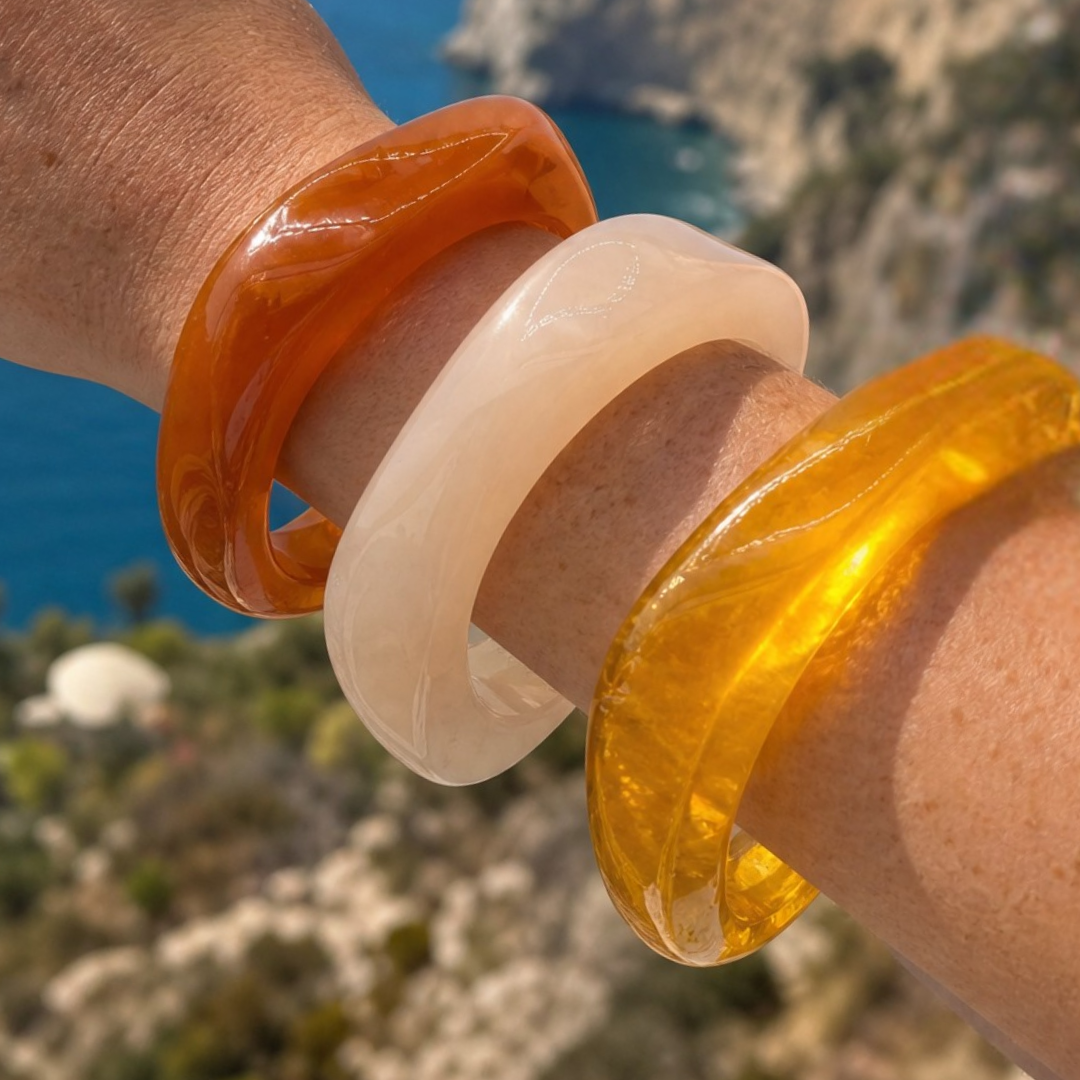 Model draagt drie bangle armbanden. Amber en wit gekleurd met marble effect.