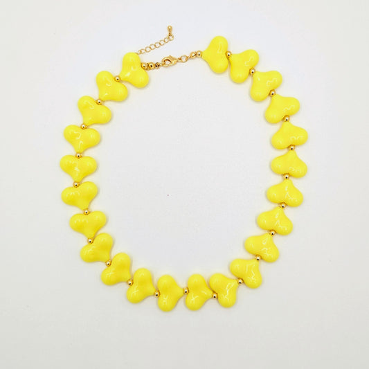 Gele hartenketting met glanzende hartkralen en goudkleurige tussenkraaltjes.
