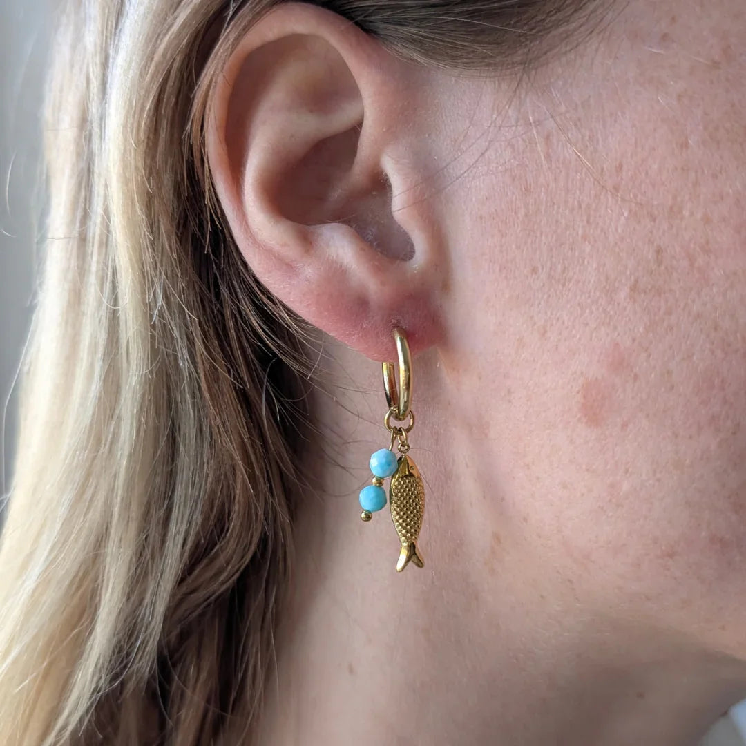 Gouden oorbel met turquoise kralen en hangende visbedel aan het oor | Casa Jadel