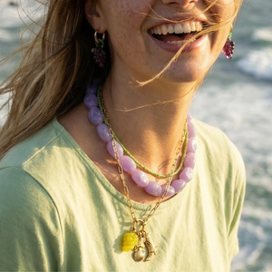 Paarse chunky ketting met kleine groene kralenketting gedragen met bedelketting en oorbellen druiven.