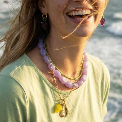 Paarse chunky ketting met kleine groene kralenketting gedragen met bedelketting en oorbellen druiven.