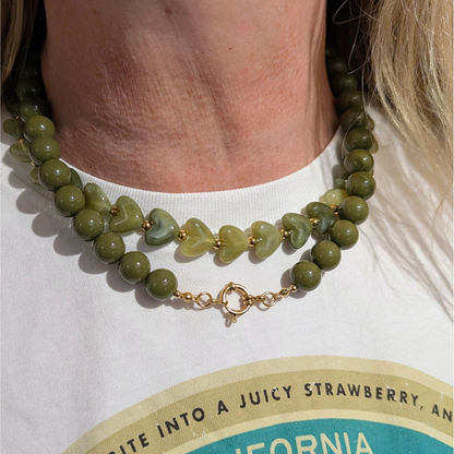 Groene hartjes kralenketting met transparante hartvormige kralen en goudkleurige details op model