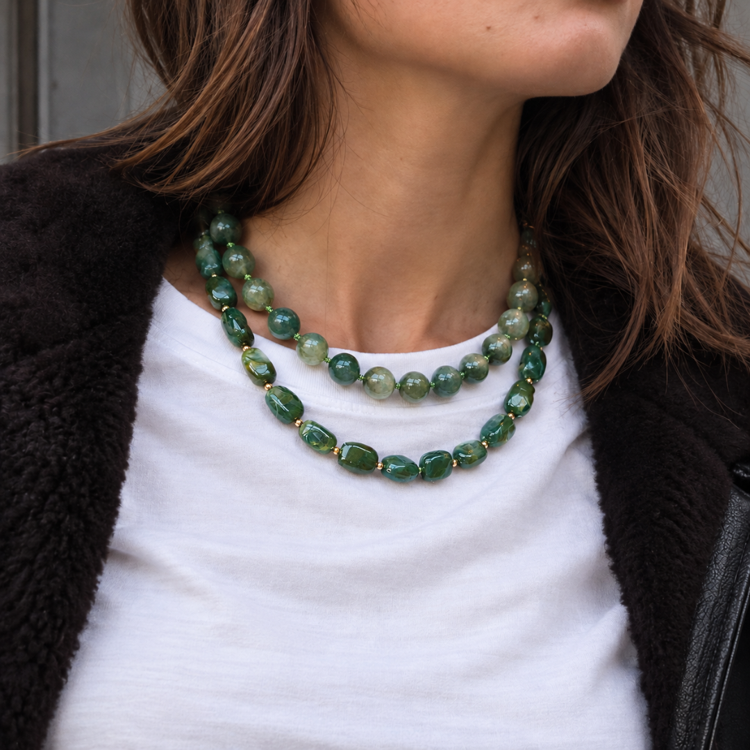 model met wit shirt en groene kettingen