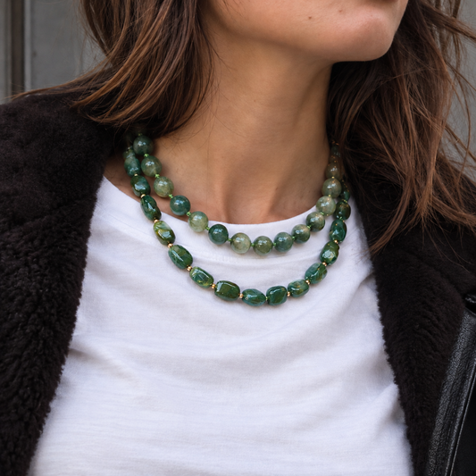 model met wit shirt en groene kettingen