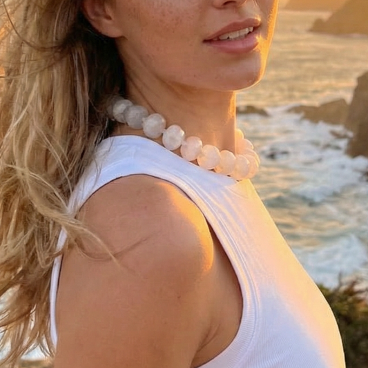 Model draagt Grote kralenketting ovel kralen Lies van Casa Jadel op het strand tijdens golden hour.