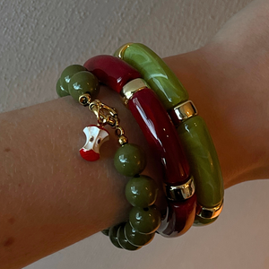 Kralenarmband legergroen met klokhuis bedel en groen en donker rode tube armband op arm
