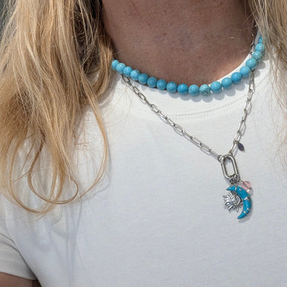 Model met zilveren schakel ketting met bedels turquoise maan zon en roze kraal en turquoise kralenketting op model