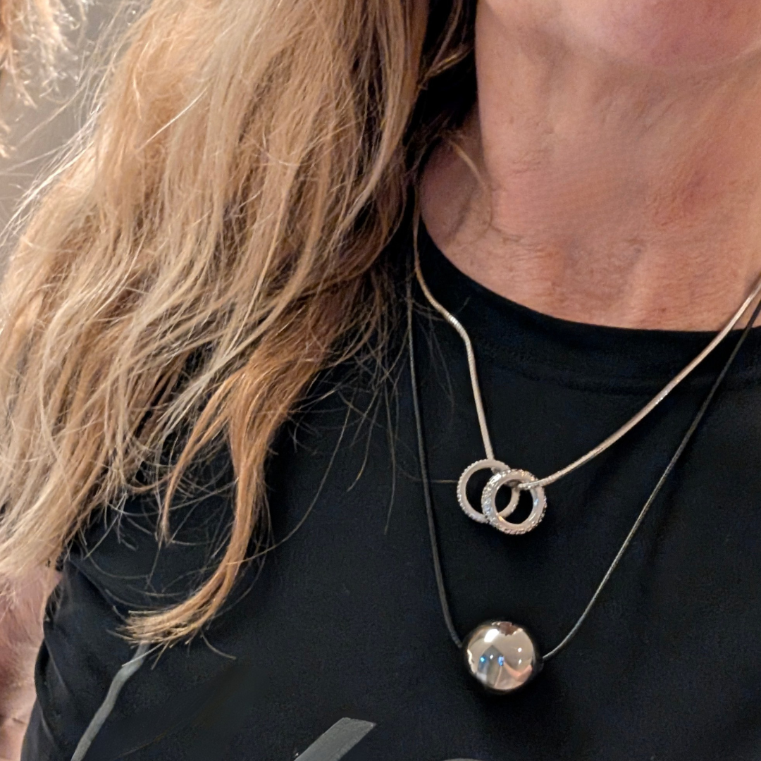 Model met zilveren kettting met 2 ringen en met koord ketting met bal
