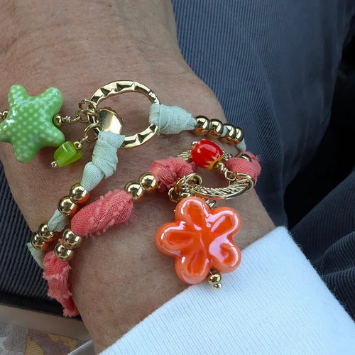 Oranje armband van stof met goud bloem schelp en kraaltjes