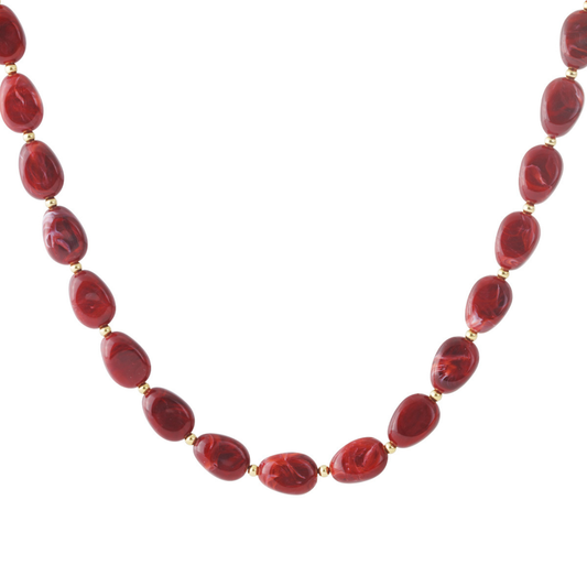 Rode gemarmerde kralenketting met goudkleurige details, gedragen op een witte top