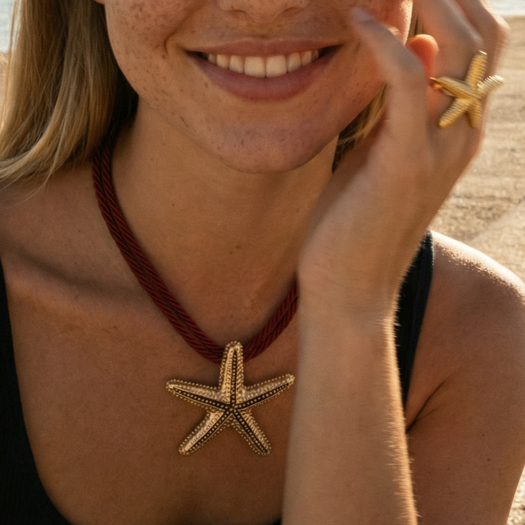 Rode koordketting met grote goudkleurige zeester hanger, gedragen op het strand – zomerse statement ketting met Ibiza beach vibe