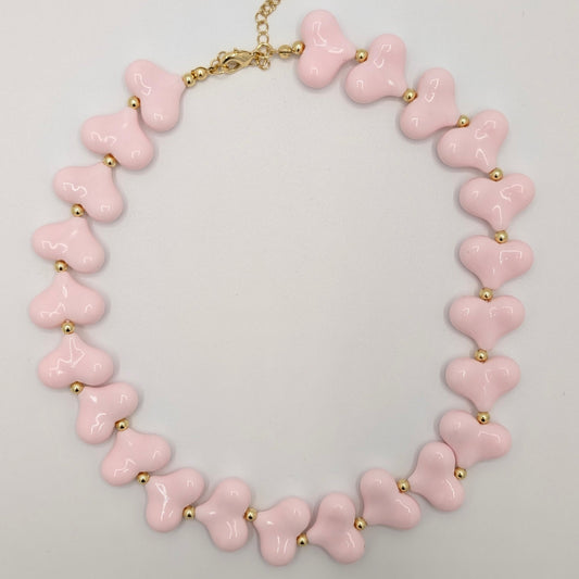 Lichtroze hartenketting met glanzende hartkralen en goudkleurige tussenkraaltjes.