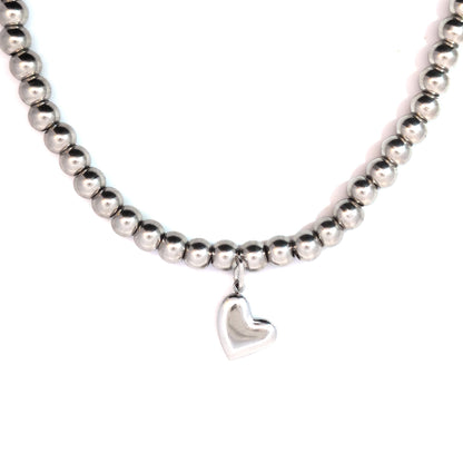 Zilveren hartje bedel gedragen aan een zilverkleurige kralenketting