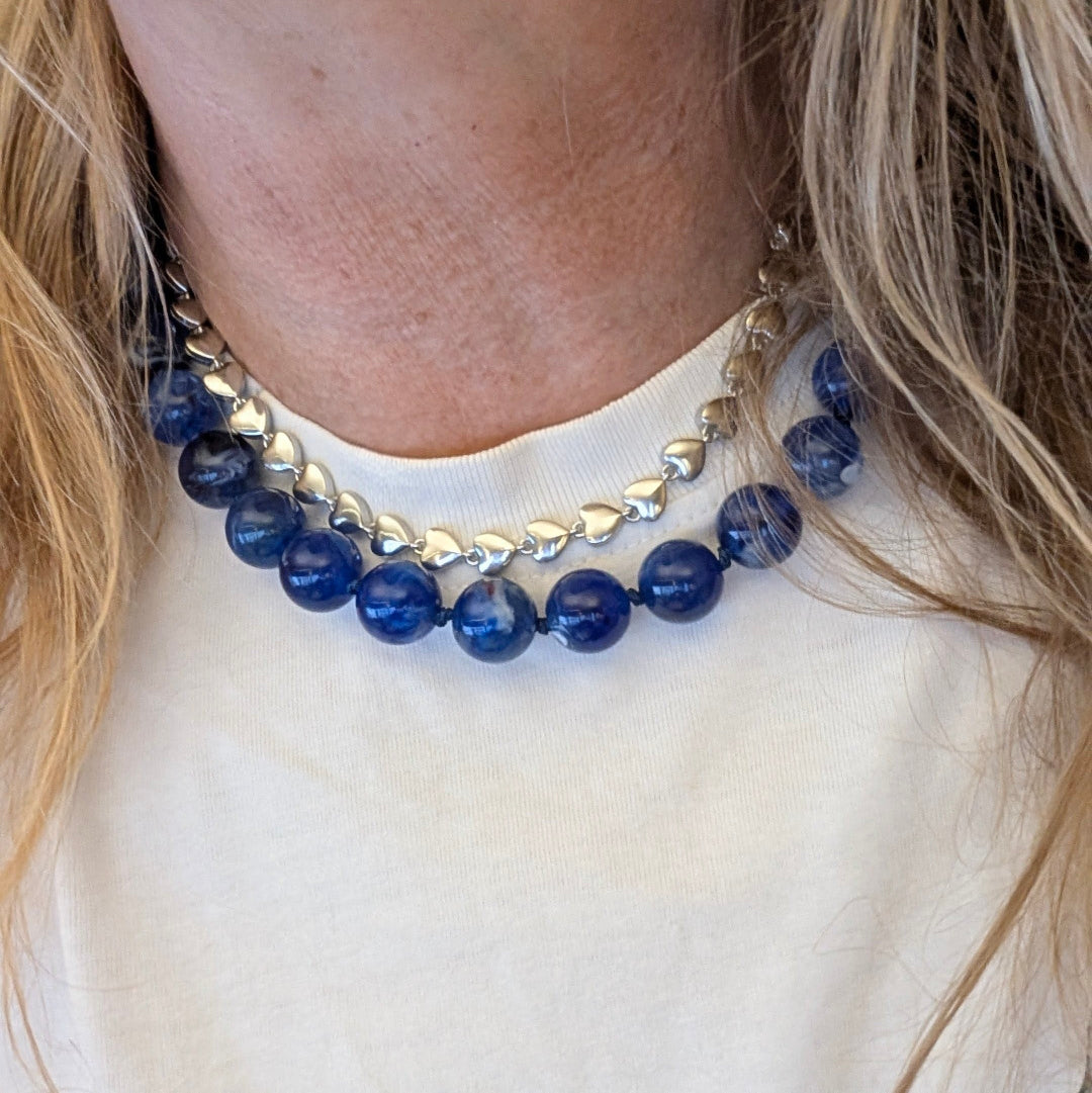 Zilveren kleine hartjesketting rondom en blauwe gemarmerde ketting op model