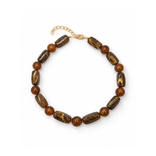 Amber-bruine kralenketting met langwerpige gemarmerde kralen, ronde amberkleurige kralen en een goudkleurige sluiting met verlengkettinkje.