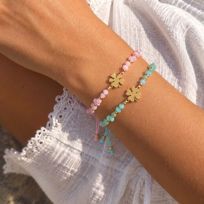 arm met babyroze en Turquoise touw armbandjes met gouden klavertje, glanzende kraaltjes en gouden details van Casa Jadel.