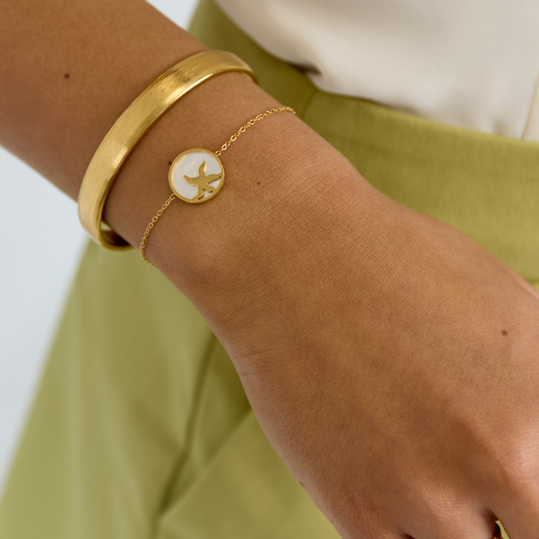 Model met arm met gouden bangle en gouden armbandje met zeester bedel