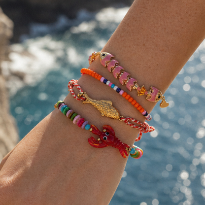 Model draagt roze en oranje armbanden met vis en kreeft bedels van Casa Jadel