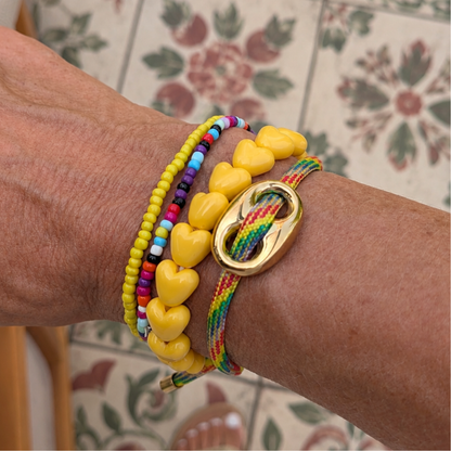 Armbandenset met gele hartjesarmband, gele kralenarmband, kleurrijke miyuki kralenarmband en rainbow koordarmband met goudkleurige statement bean