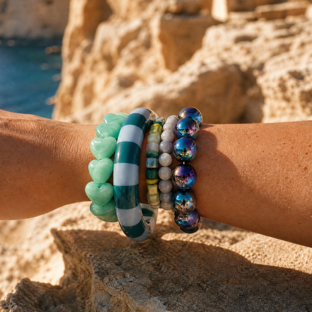 Armbandenset met mintgroene hartjesarmband, groen-wit gestreepte bangle, natuursteen kralenarmband, lichtgrijze kralenarmband en iriserende donkerblauwe parelarmband van Casa Jadel