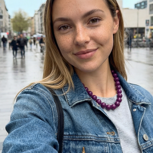 Aubergine kleurige kralenketting Ibiza style gedragen door model in stedelijke omgeving