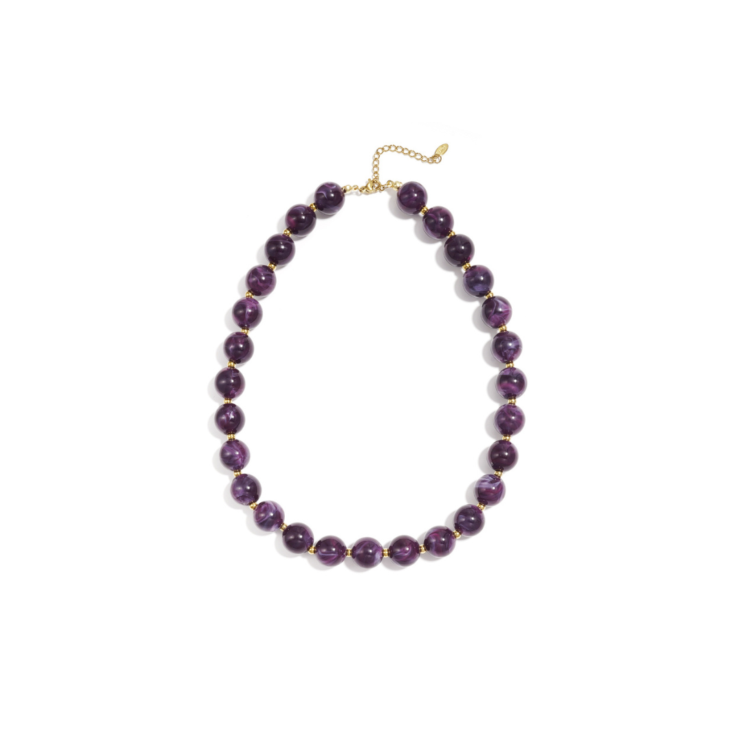 Aubergine paarse kralenketting met goudkleurige accenten op lichte achtergrond.
