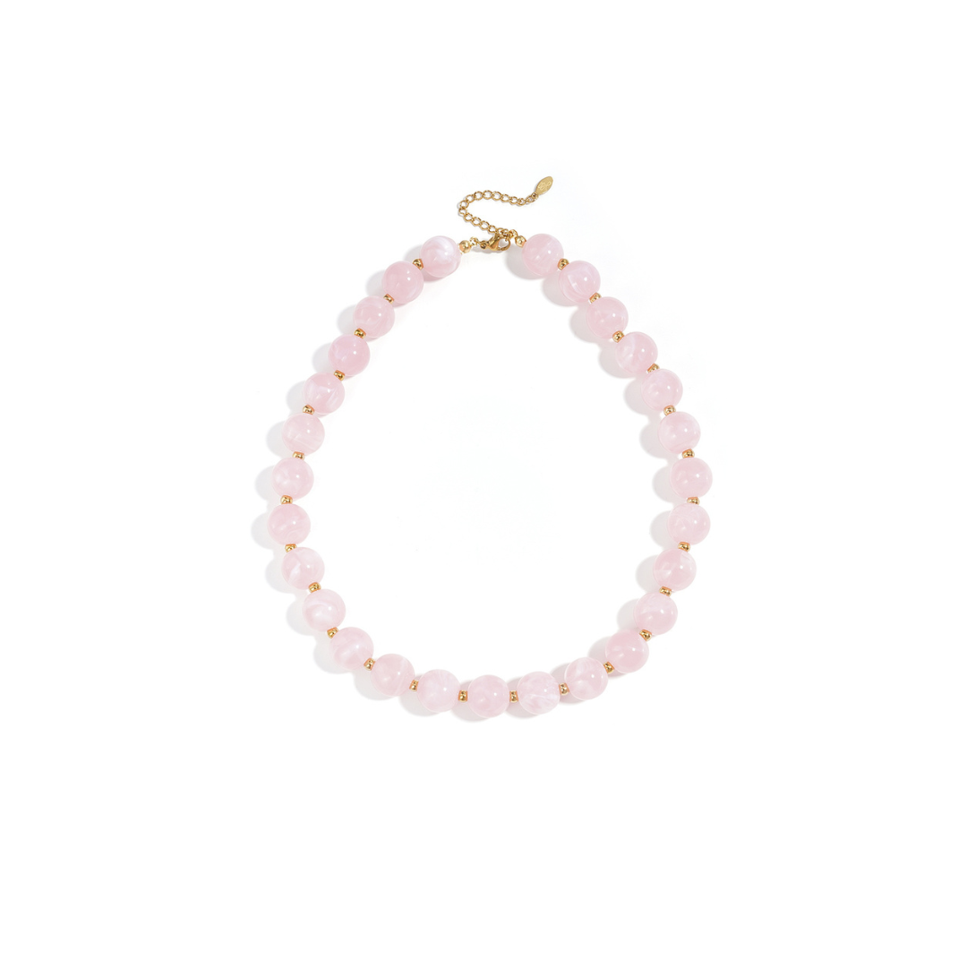 Babyroze kralenketting met goudkleurige accenten op lichte achtergrond.