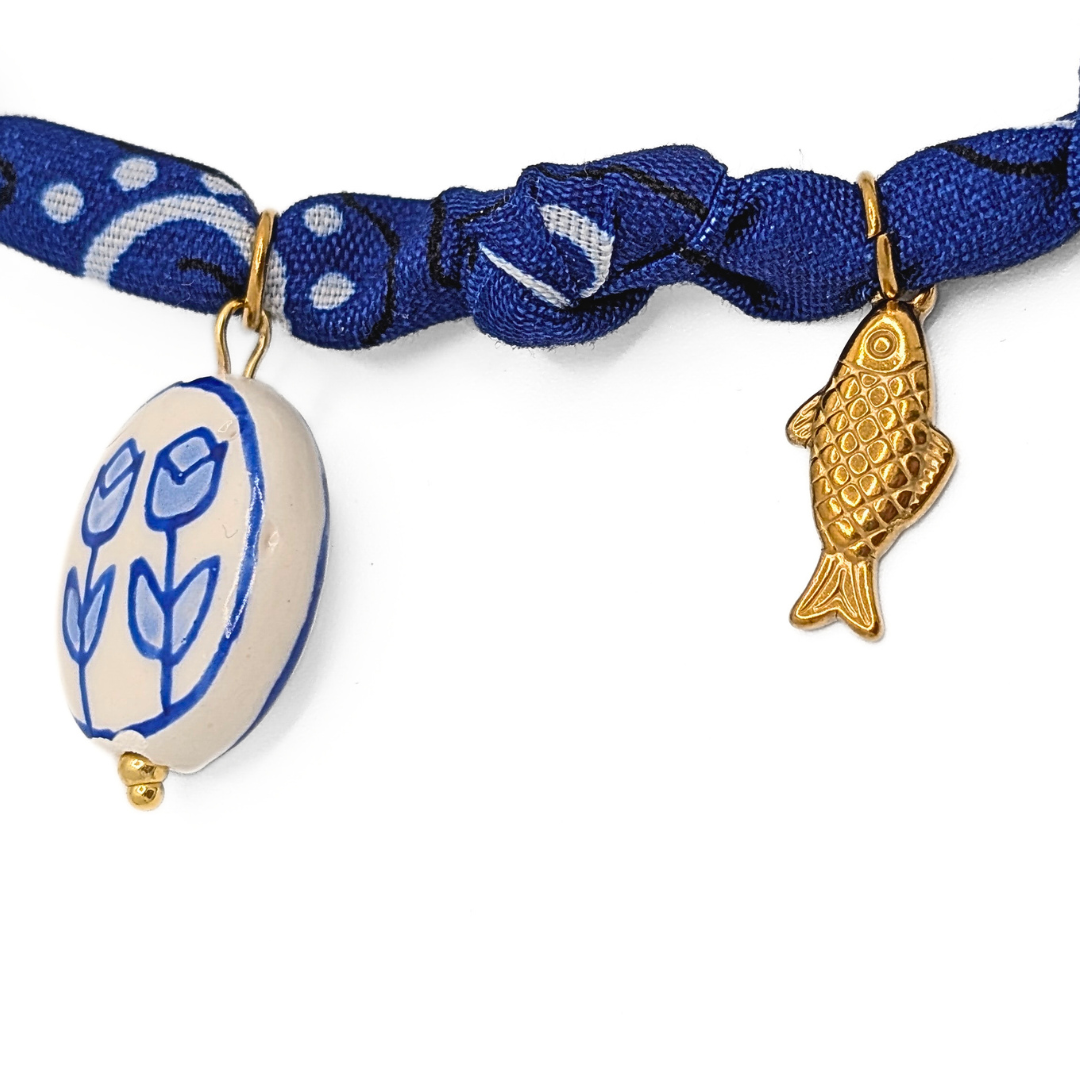 Detail van blauwe bandana ketting met gouden visbedel en keramische bedel