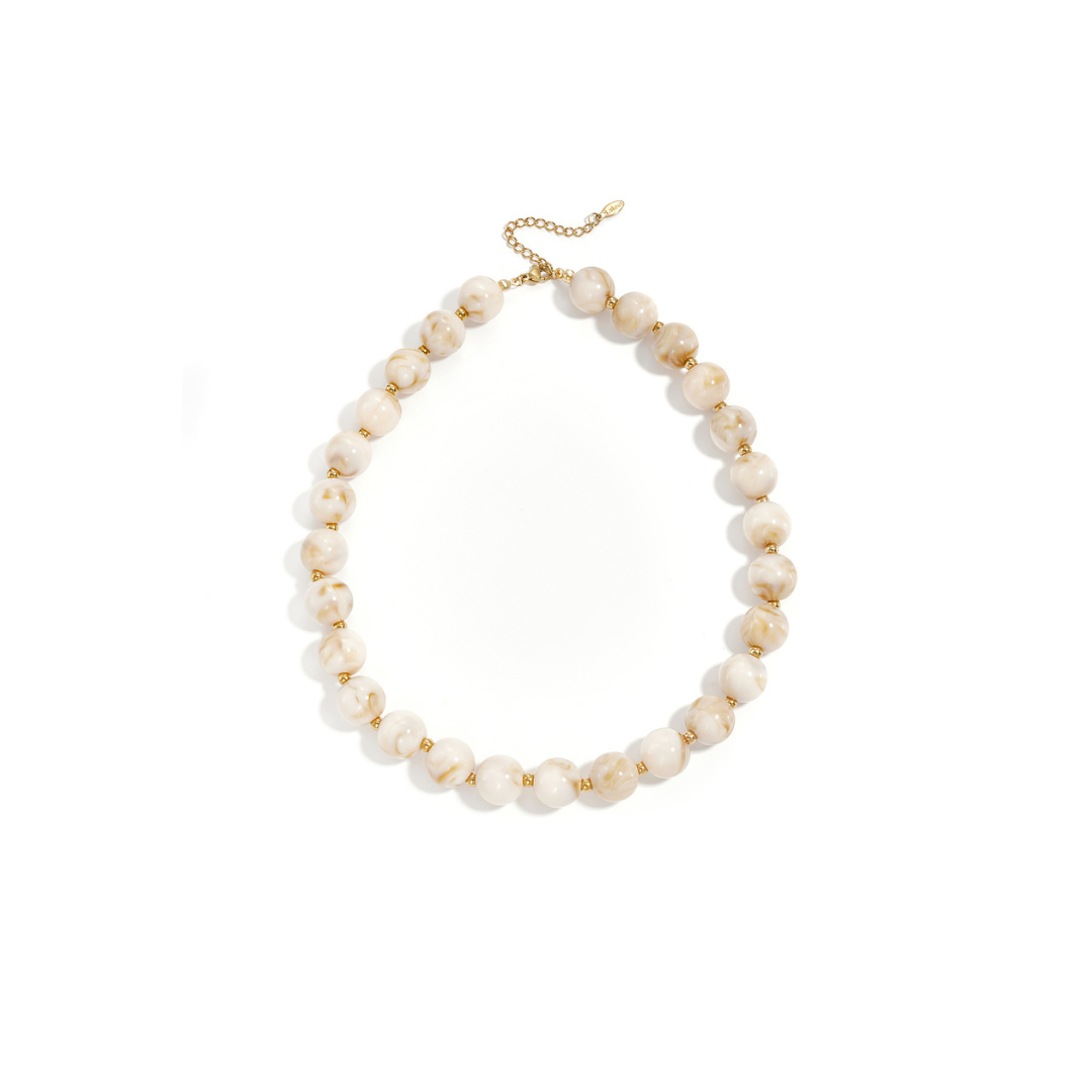 Beige gemarmerde kralenketting met goudkleurige accenten op lichte achtergrond.